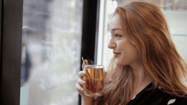 Woman drinking organic tea with glass mug